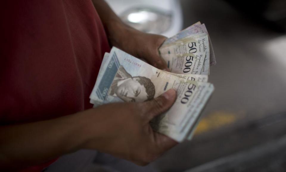 A employee accounts bolivar bills at a petrol station in Caracas, Venezuela.