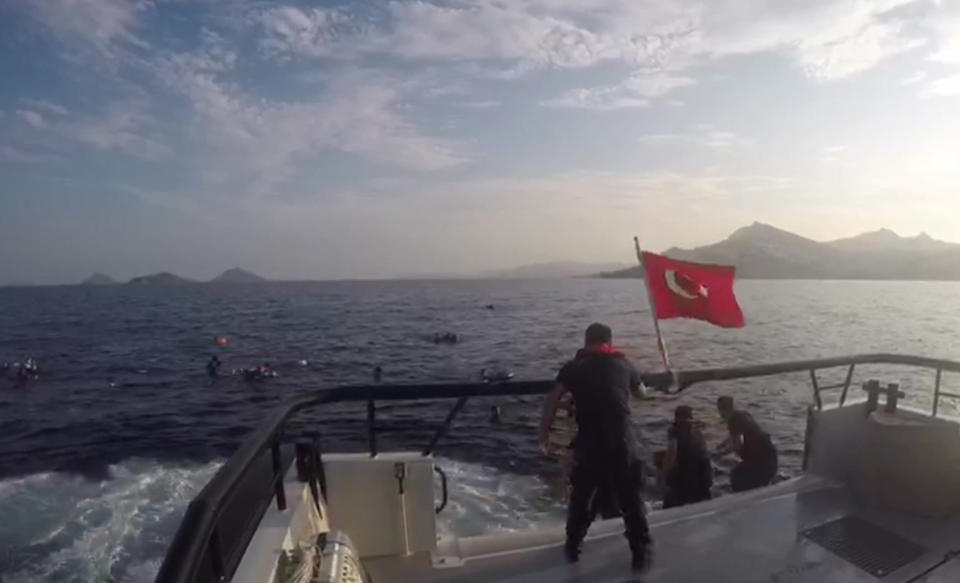 In this image taken from video made available by the Turkish Coastguard on Monday June 17, 2019, a coast guard boat approaches migrants in the Aegean Sea. A boat carrying migrants to Greece sank off the Turkish coast on Monday leaving at least eight migrants dead Turkey's coast guard said. The coast guard said 31 other migrants were rescued after the boat sank in the Aegean Sea, off the coast of Bodrum. (Turkish Coastguard via AP)