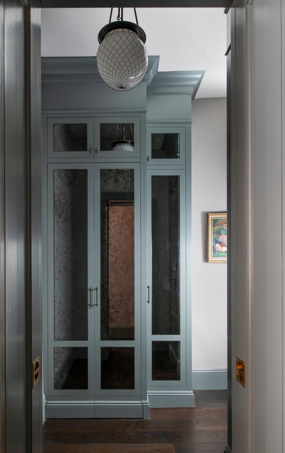 AFTER: The guest sleeping nook is flanked by mirrored custom millwork that conceals a stacked washer and dryer, and an enormous coat closet.