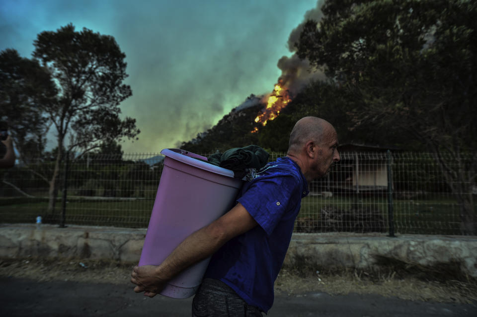 A man walks away as an advancing fire rages Hisaronu area, Turkey, Monday, Aug. 2, 2021. For the sixth straight day, Turkish firefighters battled Monday to control the blazes that are tearing through forests near Turkey's beach destinations. Fed by strong winds and scorching temperatures, the fires that began Wednesday have left eight people dead. Residents and tourists have fled vacation resorts in flotillas of small boats or convoys of cars and trucks.(AP Photo)