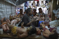 Maximino Vértiz Quintanilla repara la estatua del niño Dios de un cliente dentro de su tienda en preparación para la fiesta del "Día de la Candelaria" en la Ciudad de México, el miércoles 25 de enero de 2023. (AP Foto/Marco Ugarte)