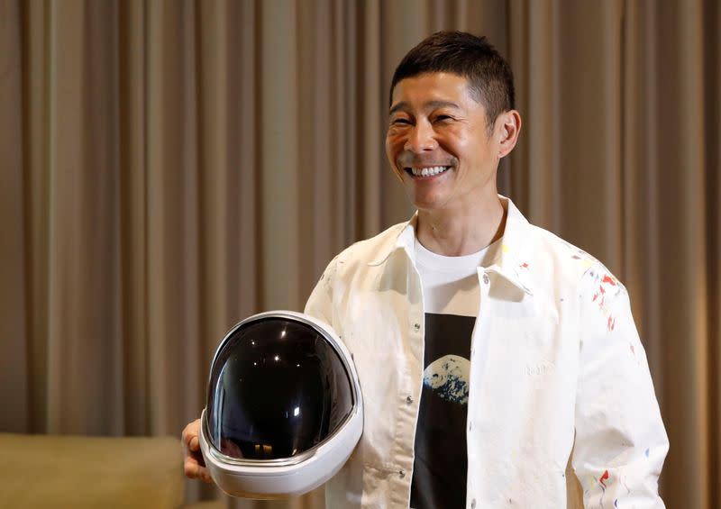 Japanese billionaire Yusaku Maezawa poses with a space suit helmet during the interview with Reuters in Tokyo