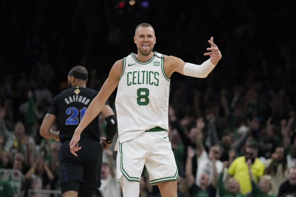 Boston Celtics center Kristaps Porzingis (8) celebrates a three-pointer, near Dallas Mavericks center Daniel Gafford (21) during the first half of Game 1 of the NBA Basketball Finals on Thursday, June 6, 2024, in Boston.  (AP Photo/Charles Krupa)