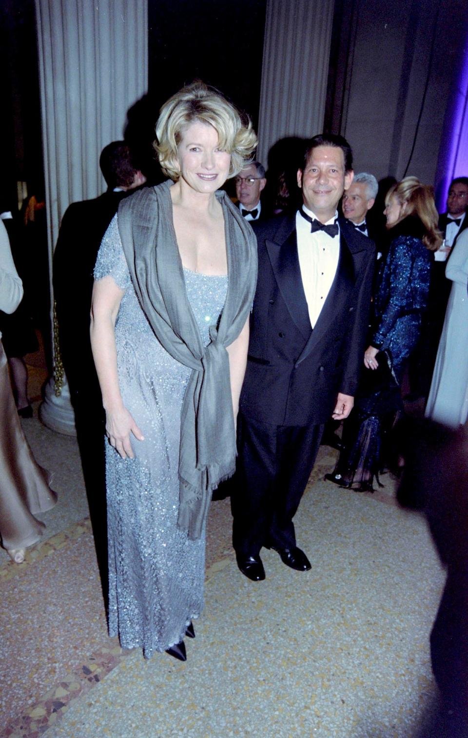 Martha Stewart, wearing a sparkly, short-sleeved blue gown, smiles at the Met Gala, surrounded by guests.