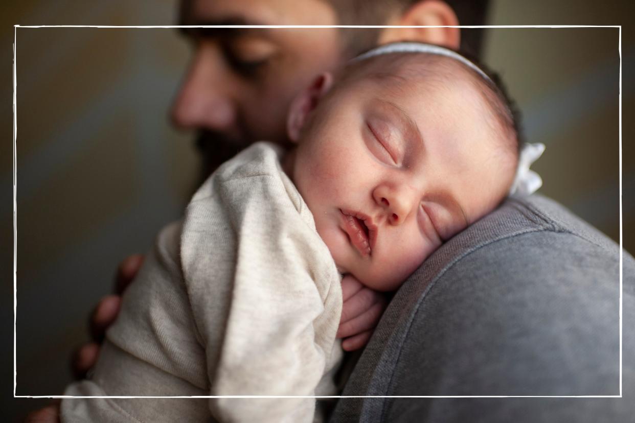  Newborn baby's face sleeping on father's shoulder. 