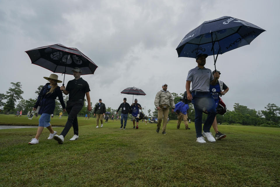 Course leaders Patrick Cantlay, left, and his teammate Xander Schauffele, right, walk off the course as play is suspended due to inclement weather during the second round of the PGA Zurich Classic golf tournament at TPC Louisiana in Avondale, La., Friday, April 21, 2023. (AP Photo/Gerald Herbert)