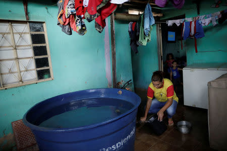 Lorena Horrara uses a bucket to collect water in an improvised reservoir on the day of water rationing, in the Ceilandia neighborhood in Brasilia, Brazil March 21, 2018. REUTERS/Ueslei Marcelino