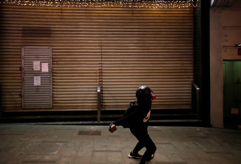 An anti-government protester throws a stone at the HSBC building during an anti-government demonstration on New Year's Day to call for better governance and democratic reforms in Hong Kong