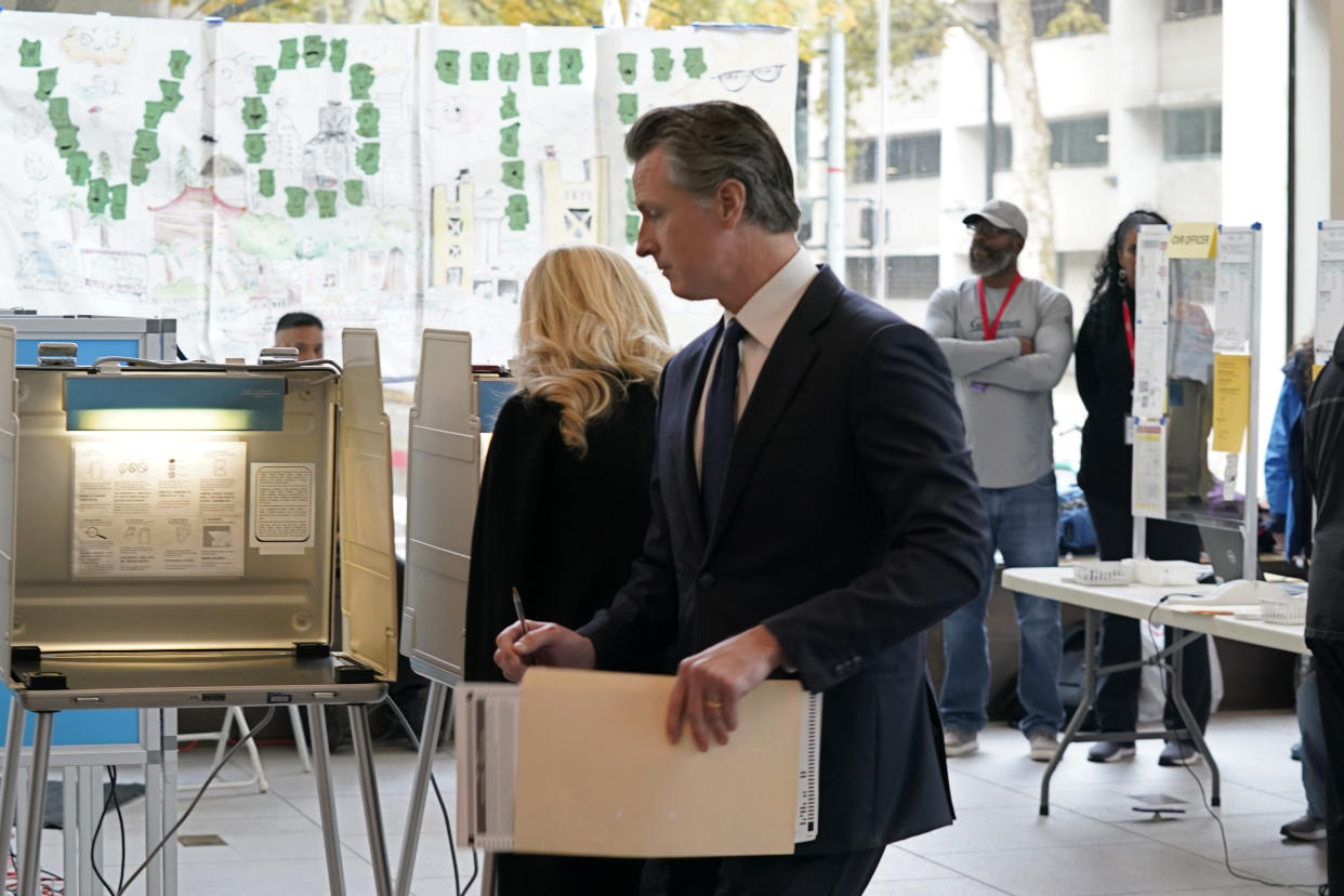 With ballot in hand, California Gov. Gavin Newsom walks to a voting booth in Sacramento, Calif.,Tuesday, Nov. 8, 2022. Newsom is running for reelection against Republican state Sen. Brian Dahle. (AP Photo/Rich Pedroncelli)