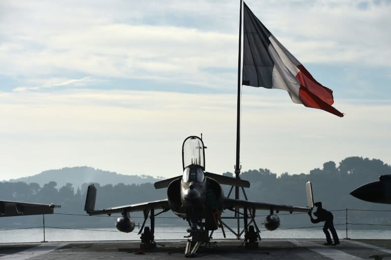 Naval technicians work on the flight deck of the French aircraft carrier Charles de Gaulle at a military port in Toulon on November 18, 2015, before departing for the Eastern Mediterranean Sea