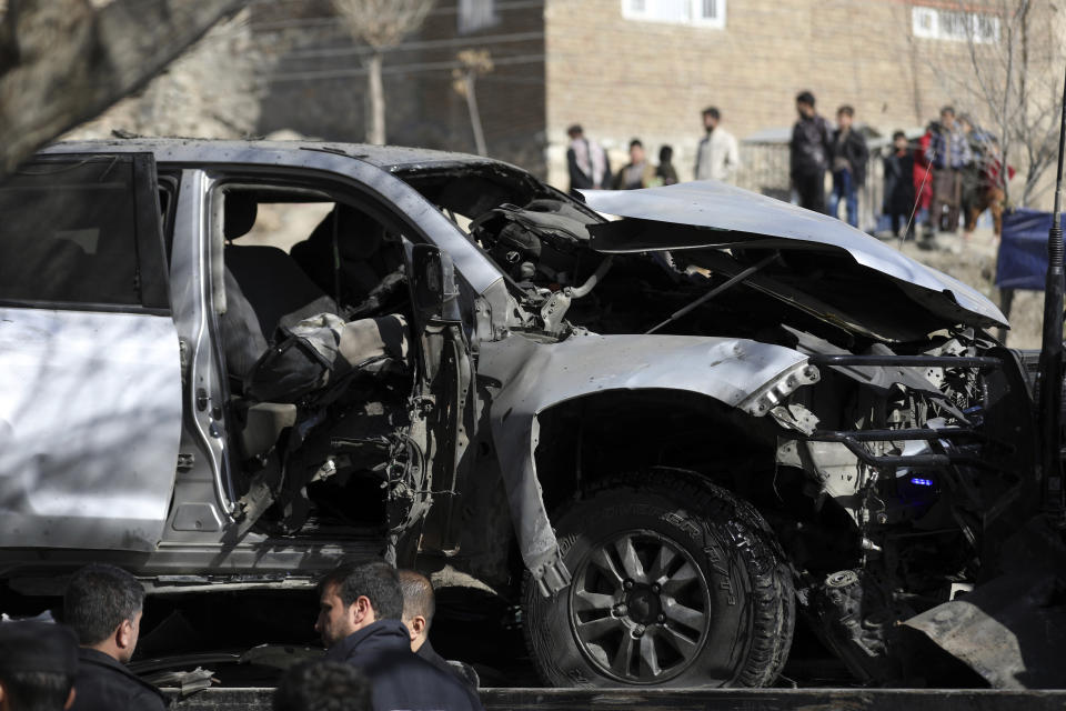 Afghan security officers inspect the site of a bomb attack in Kabul, Afghanistan, Saturday, Jan. 16, 2021. A sticky bomb attached to an armored police Land Cruiser SUV exploded Saturday in the western part of the capital, Kabul, killing few policemen and wounding another, Kabul police spokesman Ferdaws Faramarz said. (AP Photo/Rahmat Gul)