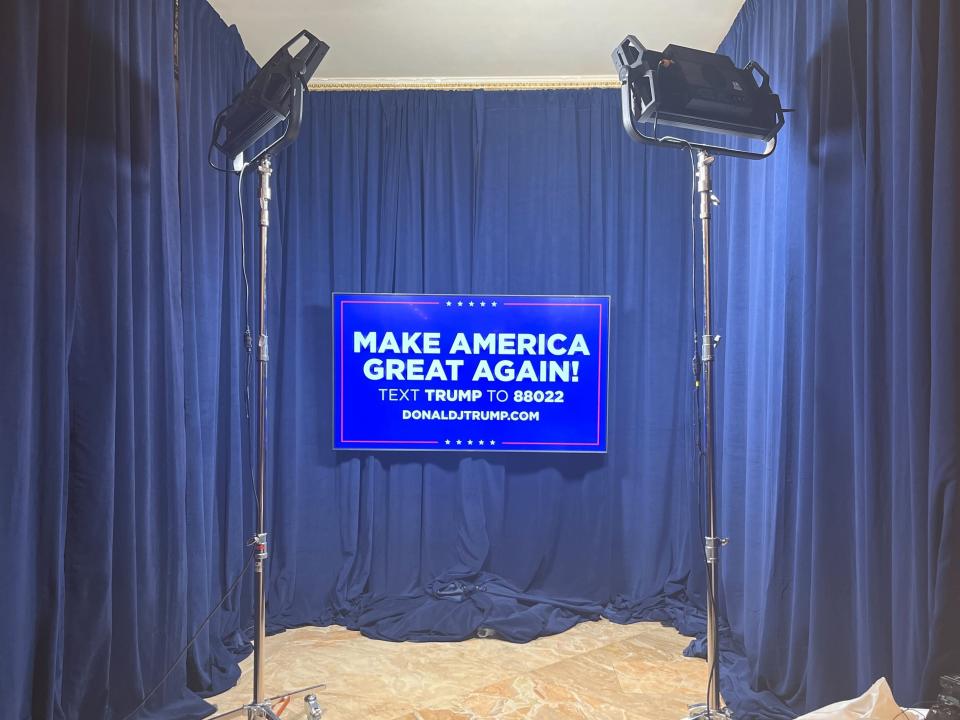 A Blue MAGA sign lit with large lights surrounded by blue curtains