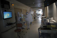 A nurse puts on protective clothing to tend to patients affected by the COVID-19 virus in the ICU unit at the Charles Nicolle public hospital, Thursday, April 15, 2021 in Rouen, France. A renewed crush of COVID-19 cases is again forcing intensive care units across France to grapple with the macabre mathematics of how to make space for thousands of critically ill patients (AP Photo/Christophe Ena)