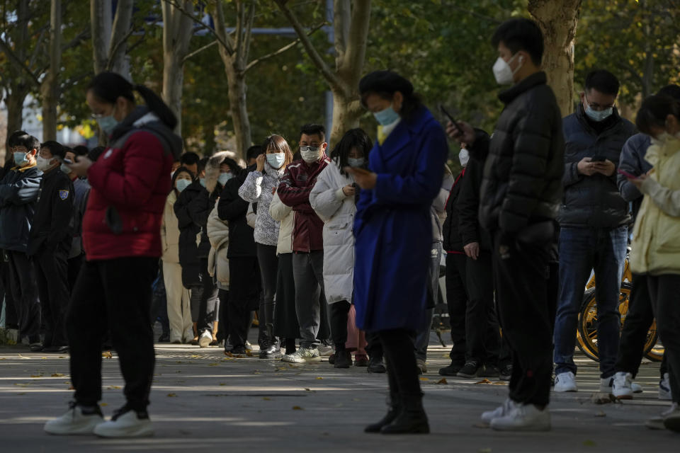 People wearing face masks stand in line for their routine COVID-19 tests at a coronavirus testing site in Beijing, Tuesday, Nov. 15, 2022. China's ruling party called for strict adherence to the hard-line "zero-COVID" policy Tuesday in an apparent attempt to guide public perceptions after regulations were eased slightly in places. (AP Photo/Andy Wong)