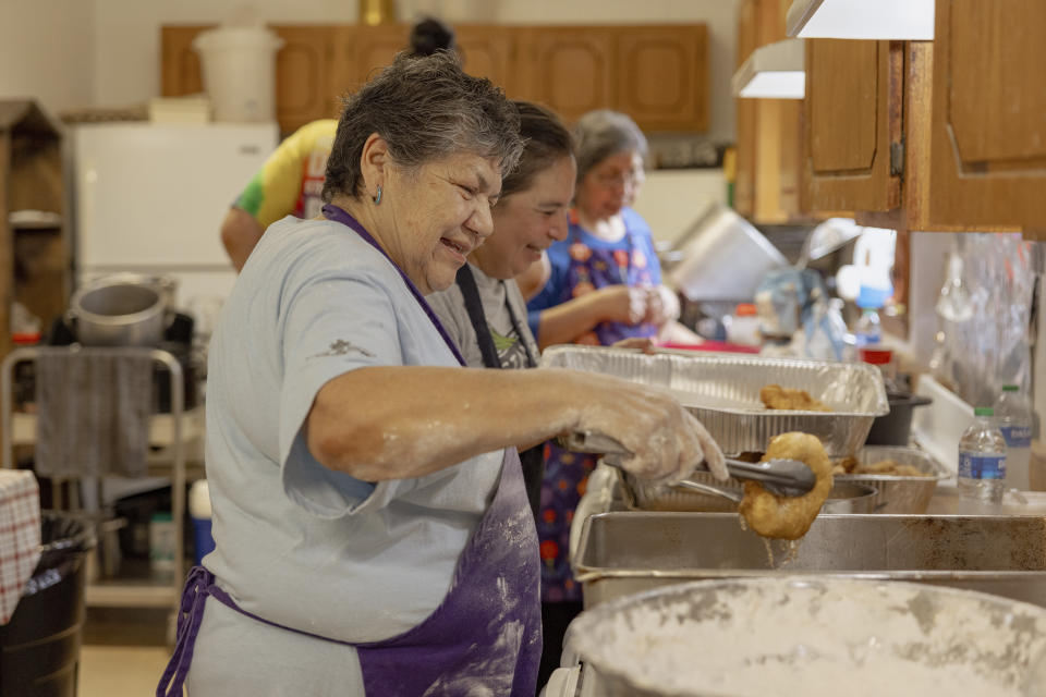 Carol Tiger, a member of Muscogee Nation and an elder at the Springfield United Methodist Church in Okemah, Okla., lets the oil drip off a freshly-cooked piece of frybread at the church's annual wild onion dinner on AprilA 6, 2024. Wild onions are among the first foods to grow in the spring, and the dinners have been a tradition in Native American communities for generations. (AP Photo/Brittany Bendabout)