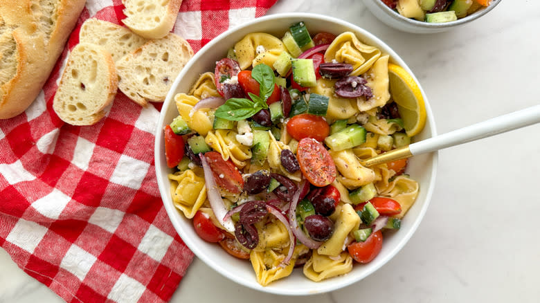 bowl of tortellini Greek salad next to gingham cloth