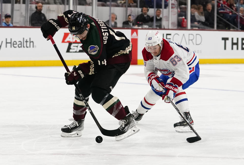 Arizona Coyotes' Shayne Gostisbehere (14) controls the puck in front of Montreal Canadiens' Evgenii Dadonov (63) in the second period during an NHL hockey game, Monday, Dec. 19, 2022, in Tempe, Ariz. (AP Photo/Darryl Webb)