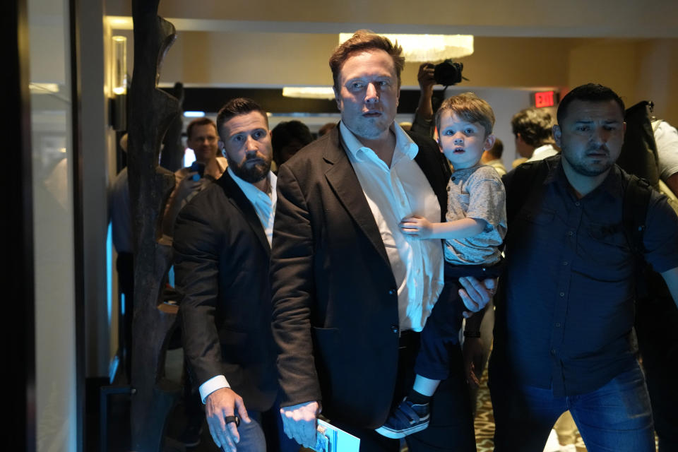 Twitter CEO Elon Musk, center, carries his child as he leaves after speaking at the POSSIBLE marketing conference, Tuesday, April 18, 2023, in Miami Beach, Fla. (AP Photo/Rebecca Blackwell)
