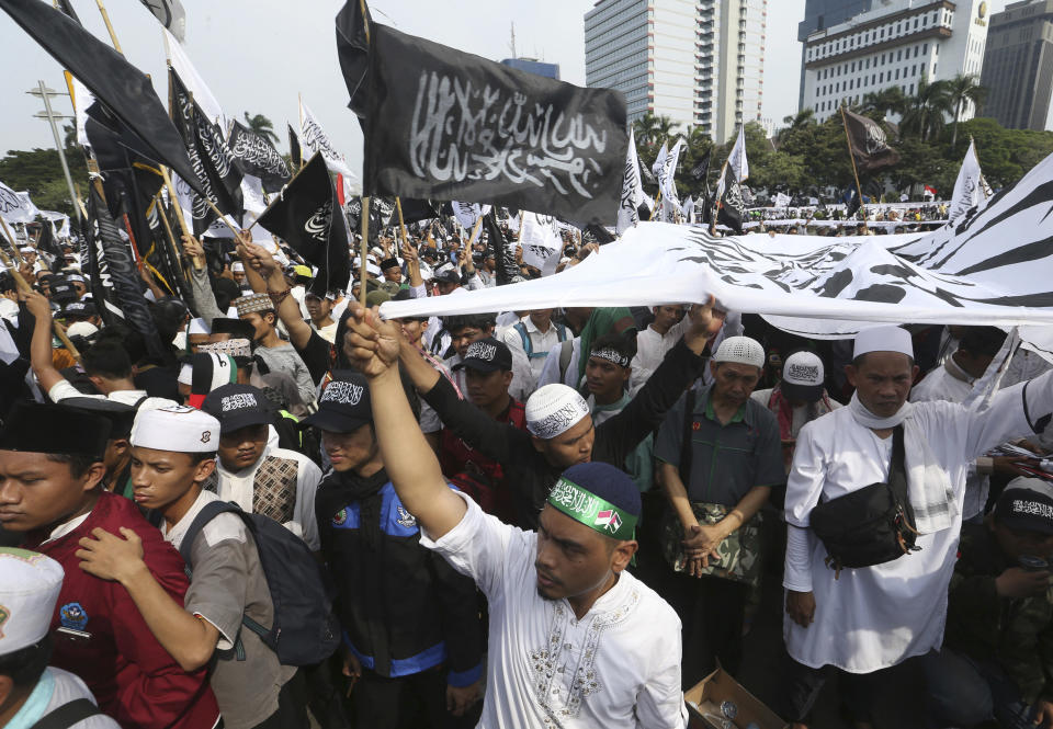 Muslim men hold flags with Arabic writings that read: "There's no god but Allah and Muhammad is his messenger" popularly known as "tauhid flag" which is often linked with banned Islamic group Hizbut Tahir Indonesia, during a protest in Jakarta, Indonesia, Friday, Nov. 2, 2018. Thousands of conservative Muslims staged the protest in the capital against the burning of the flag by members of Nahdlatul Ulama, the country's largest mainstream religious organization. (AP Photo/Achmad Ibrahim)