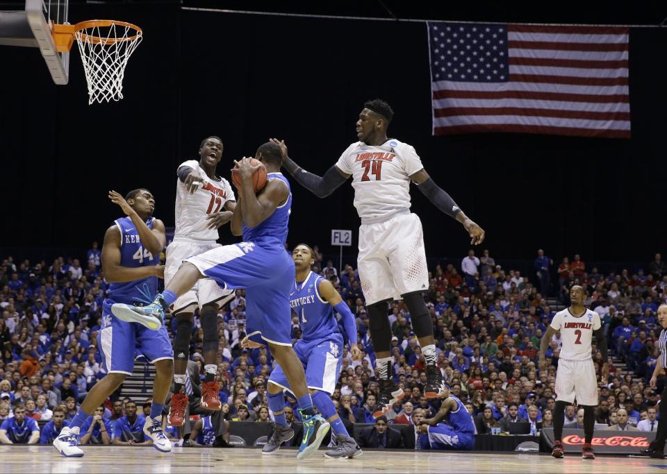 Kentucky's Julius Randle grabs a rebound in front of Louisville's Mangok Mathiang (12) and Montrezl Harrell (24) during the first half of an NCAA Midwest Regional semifinal college basketball tournament game Friday, March 28, 2014, in Indianapolis. (AP Photo/David J. Phillip)