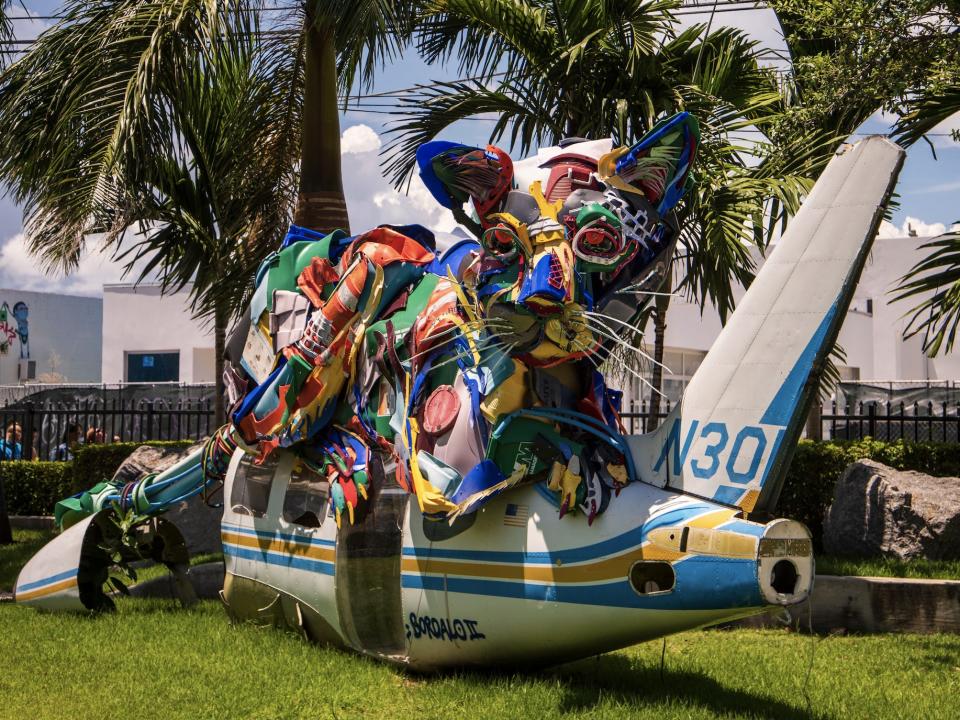 A colorful cat sculpture on a plane in a field in Miami Florida