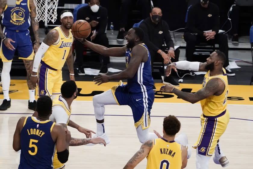 Golden State Warriors' Draymond Green, center, drives to the basket past Los Angeles Lakers' LeBron James, right, during the second half of an NBA basketball game, Monday, Jan. 18, 2021, in Los Angeles. The Warriors won 115-113. (AP Photo/Jae C. Hong)
