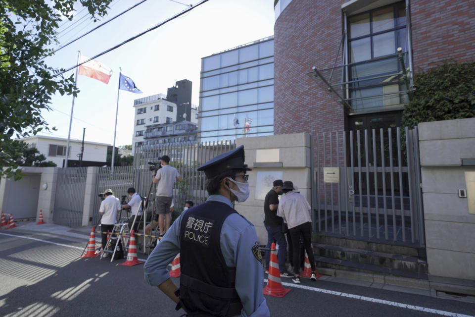 A Japanese police officer stands by media crews in front of the Embassy of Poland in Tokyo where the Belarusian athlete Krystsina Tsimanouskaya who seeks asylum is staying, Tuesday, Aug. 3, 2021. Tsimanouskaya waged - and lost - a legal fight to run in the 200 meters at the Olympics while she was also seeking a humanitarian visa to leave the Tokyo Games safely. (AP Photo/Kantaro Komiya)