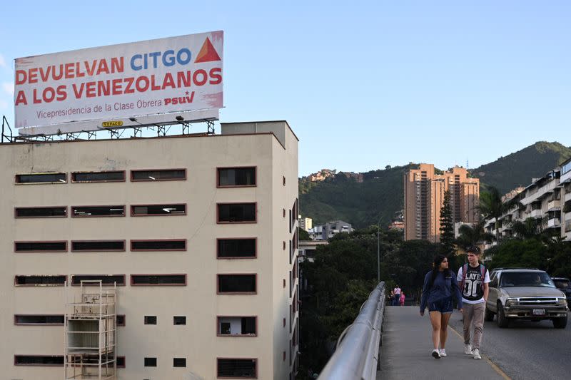 People walk past a billboard about Venezuelan refiner Citgo, in Caracas