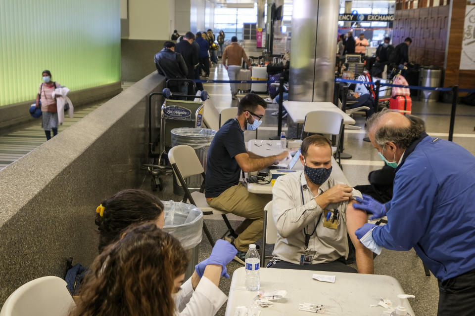 A traveler is vaccinated at the Los Angeles International Airport in Los Angeles, Wednesday Dec. 22, 2021. People traveling during the holiday season can get free COVID-19 vaccinations and booster shots at LAX on two consecutive Wednesdays -- today and Dec. 29. The pop-up clinic, located at the Lower/Arrivals Level of the Tom Bradley International Terminal, will be open from 11 a.m. to 5 p.m. on the two days. (AP Photo/Ringo H.W. Chiu)