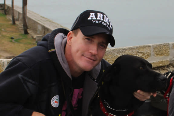 An Army veteran poses with his new canine partner.