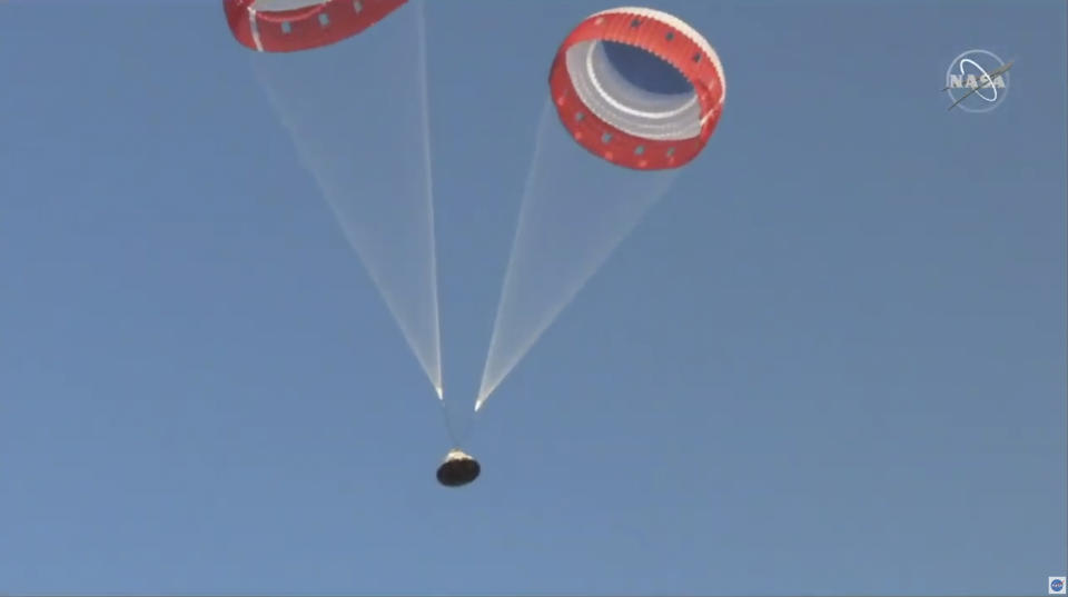 In this image made from a video provided by NASA parachutes guide the Starliner capsule to the ground after a test of Boeing's crew capsule's launch abort system in White Sands Missile Range in N.M., on Monday, Nov. 4, 2019. The capsule carried no astronauts Monday morning, just a test dummy. (NASA via AP)