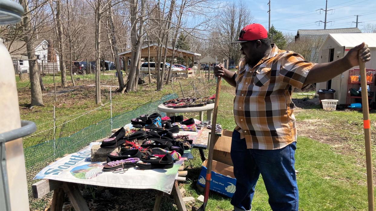 Tamba Fayla, a Liberian refugee, browses a table of free shoes on April 22, 2022, at Webster Farms Community Garden in Lansing.