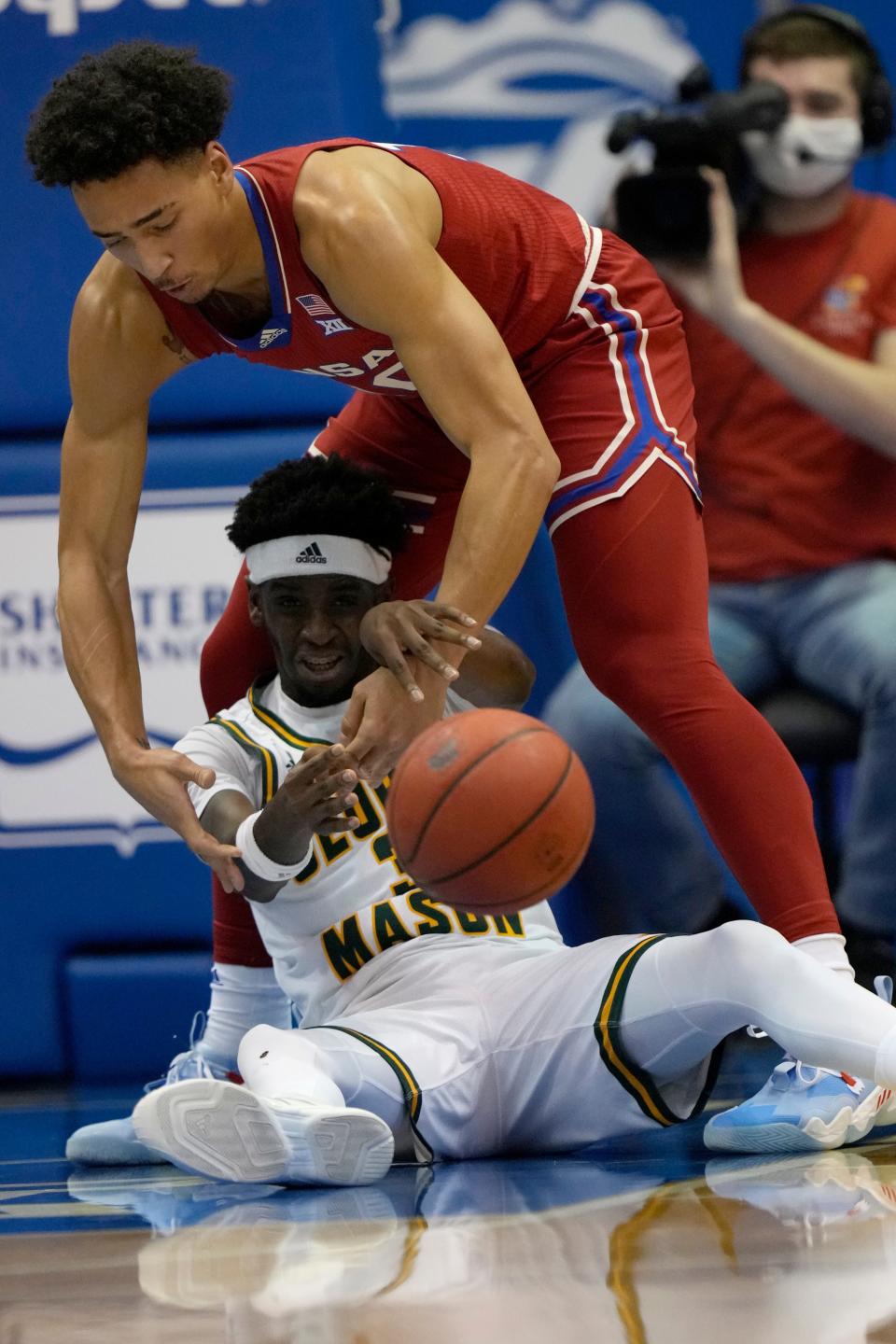 Then-George Mason guard Davonte Gaines passes to a teammate while being guarded by Kansas forward Jalen Wilson during a game in January 2022 in Lawrence, Kan.