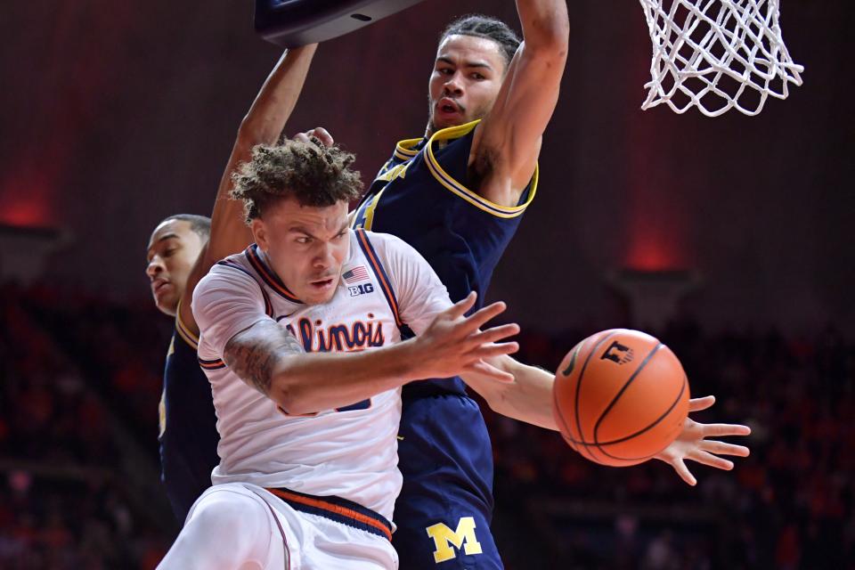Illinois Fighting Illini forward Coleman Hawkins (33) passes the ball by Michigan Wolverines forward Olivier Nkamhoua (13) during the first half at State Farm Center in Champaign, Illinois, on Tuesday, Feb. 13, 2024.