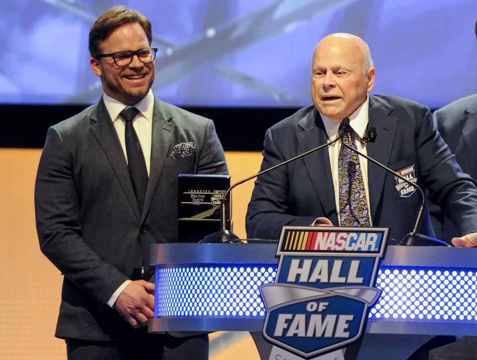 FILE - Hall of Fame inductee Bruton Smith entertains the crowd as his son, Marcus Smith, left, looks on during NASCAR Hall of Fame Induction ceremonies in Charlotte, N.C., in this Saturday, Jan. 23, 2016, file photo. NASCAR wanted new energy and ideas this season and Marcus Smith has been pivotal in helping the sport deliver. The lessons learned from Bruton Smith have helped his son as Marcus Smith takes a bigger role in NASCAR’s future planning. (AP Photo/Mike McCarn, File)