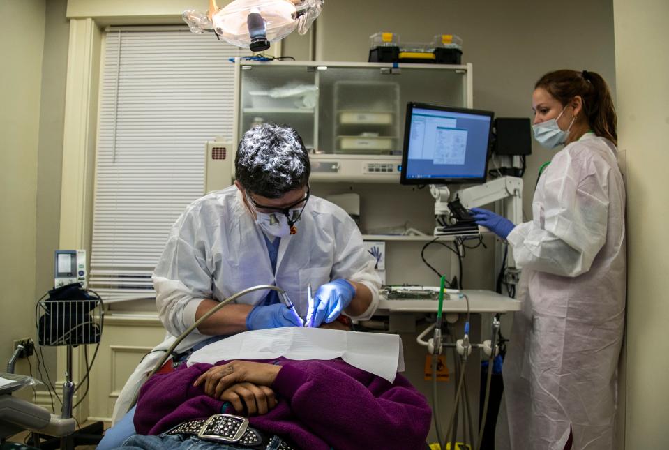 Dentist Bradley Congleton and Expanded Duty Dental Assistant Darisly Rosabal work with a patient at the Family Health Center on East Muhammad Ali. Dec. 27, 2018