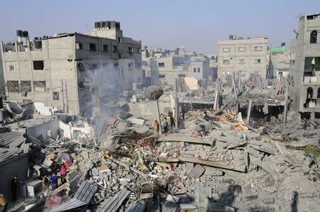 Palestinians stand on what witnesses say was a house destroyed by an Israeli air strike in Rafah, southern Gaza, in this August 2, 2014 file photo. REUTERS/Ibraheem Abu Mustafa/Files