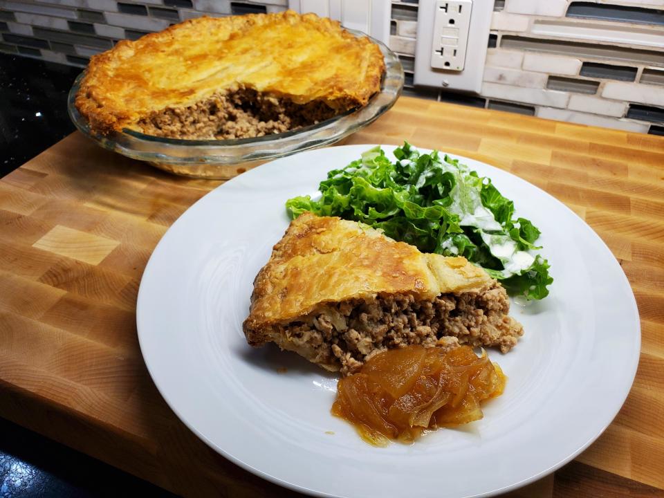 a slice of Tourtière on a plate next to a leafy salad