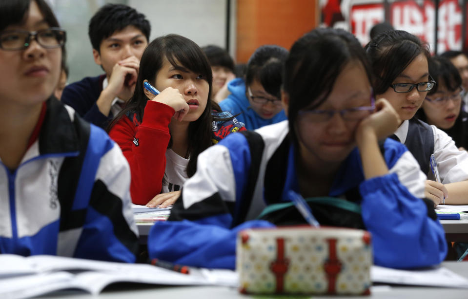 In this Dec. 9, 2013 photo, students attend an English grammar lesson by Tony Chow in a classroom of Modern Education in Hong Kong. The 30-year-old teaches English grammar to thousands of secondary school pupils, who attend his after-school lessons or watch video replays of them at Modern Education’s 14 branches. Chow is a celebrity tutor in Hong Kong, where there’s big money to be made offering extracurricular lessons to parents desperately seeking an edge for their children preparing for the city’s intense public entrance exam for university. (AP Photo/Kin Cheung)