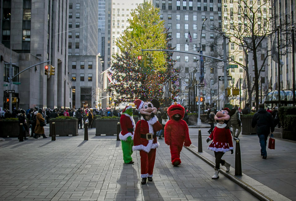 In this Friday, Dec. 20, 2019 photo, costumed performers leave Rockefeller Center in New York. Some performers, who solicit tips from tourists from designated "activity zones" in Times Square, have been migrating to Rockefeller Center for the holiday season where no such zones exist. (AP Photo/Bebeto Matthews)
