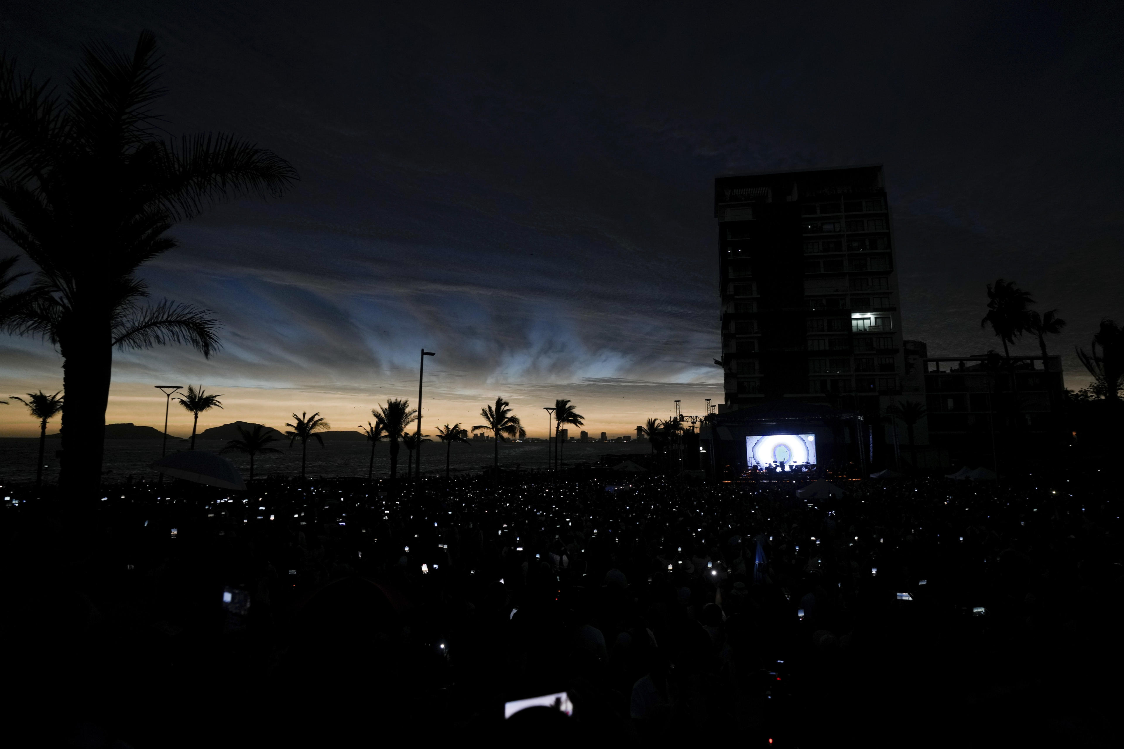 People use their cell phones as the sky darkens during a total solar eclipse in Mazatlan, Mexico, Monday, April 8, 2024. (Fernando Llano/AP)