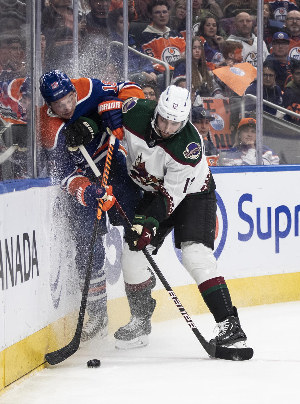 Arizona Coyotes' Connor Mackey (12) checks Edmonton Oilers' Zach Hyman (18) during the second period of an NHL hockey game in Edmonton, Alberta, Wednesday, March 22, 2023. (Jason Franson/The Canadian Press via AP)