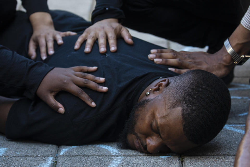Jimmy Barwan, cousin of Patrick Lyoya is comforted by protesters during a moment of silence outside Grand Rapids Police Department in Grand Rapids, Mich. on Thursday, June 9, 2022. A prosecutor filed a second-degree murder charge Thursday against the Michigan police officer who killed Patrick Lyoya, a Black man who was on the ground when he was shot in the back of the head following an intense physical struggle recorded on a bystander's phone. (Joel Bissell/The Grand Rapids Press via AP)