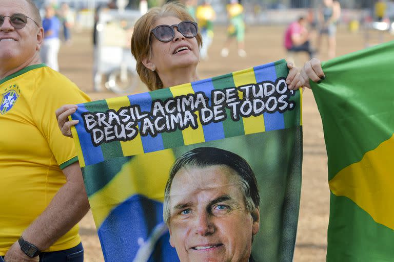 Una simpatizante de Jair Bolsonaro sostiene una bandera con su imagen mientras espera los resultados tras el cierre de urnas por la segunda vuelta de las elecciones presidenciales en Brasilia, Brasil, el domingo 30 de octubre 2022. 