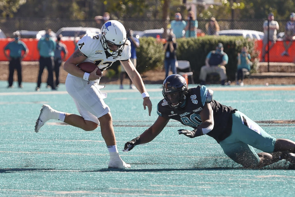 Appalachian State quarterback Zac Thomas, left, scrambles while defended by Coastal Carolina's Rolan Wooden ll during the first half of an NCAA college football game Saturday, Nov. 21, 2020, in Conway, S.C. (AP Photo/Richard Shiro)