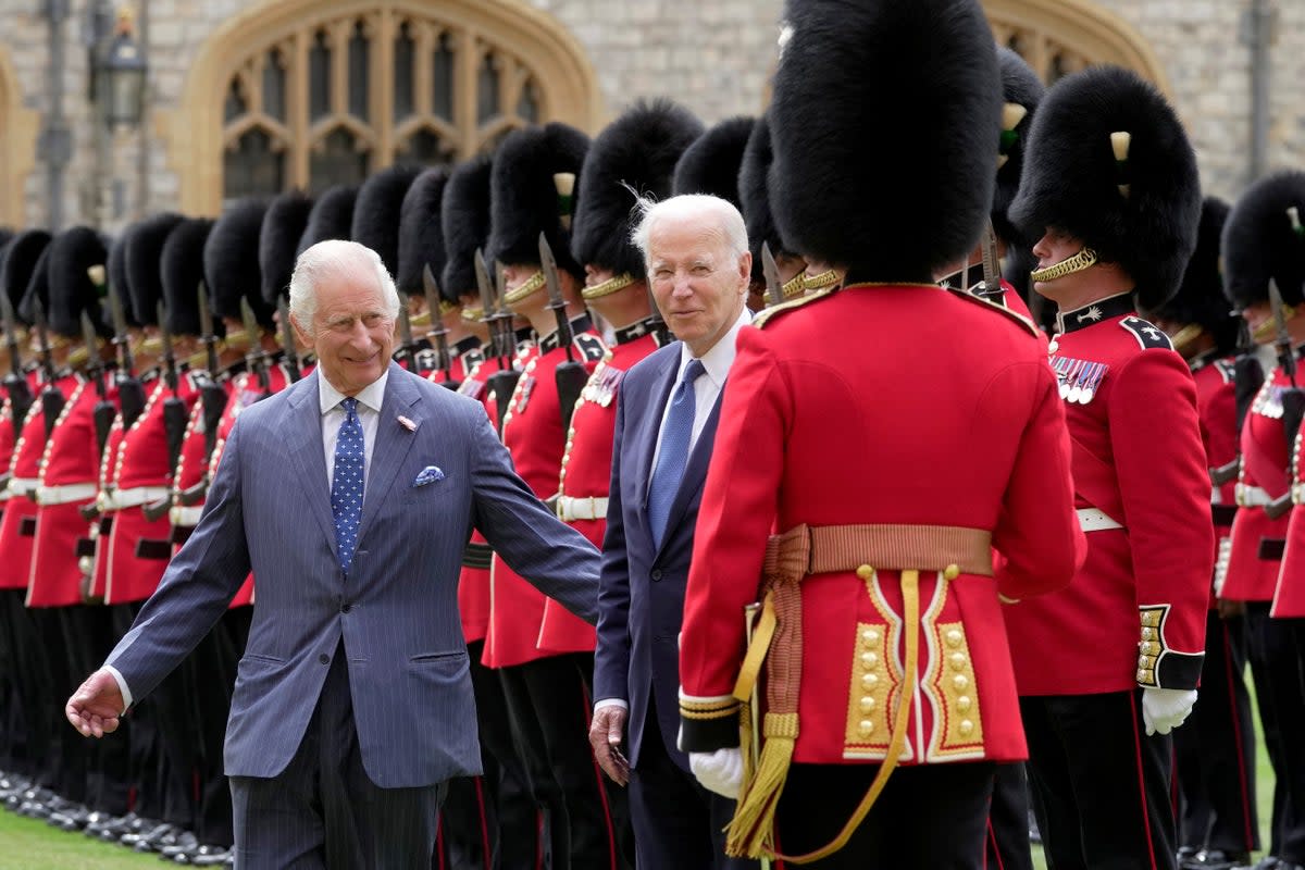 El rey Carlos abre el paso al presidente Biden mientras el mandatario estadounidense charla con un guardia (Vía REUTERS)