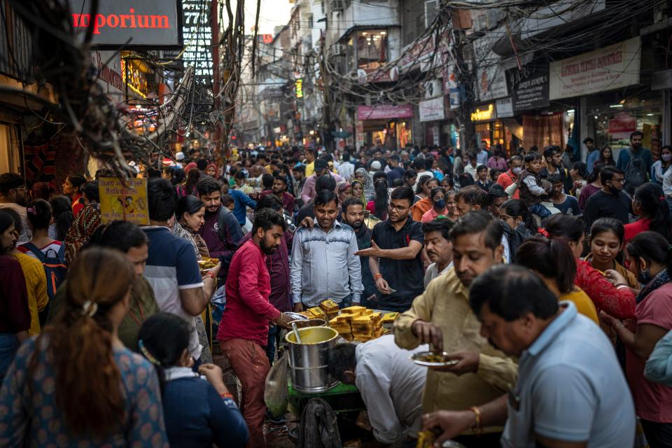 November 12, 2022: People eat street food as shoppers crowd a market in New Delhi, India. The world's population is projected to hit an estimated 8 billion people according to a United Nations projection.