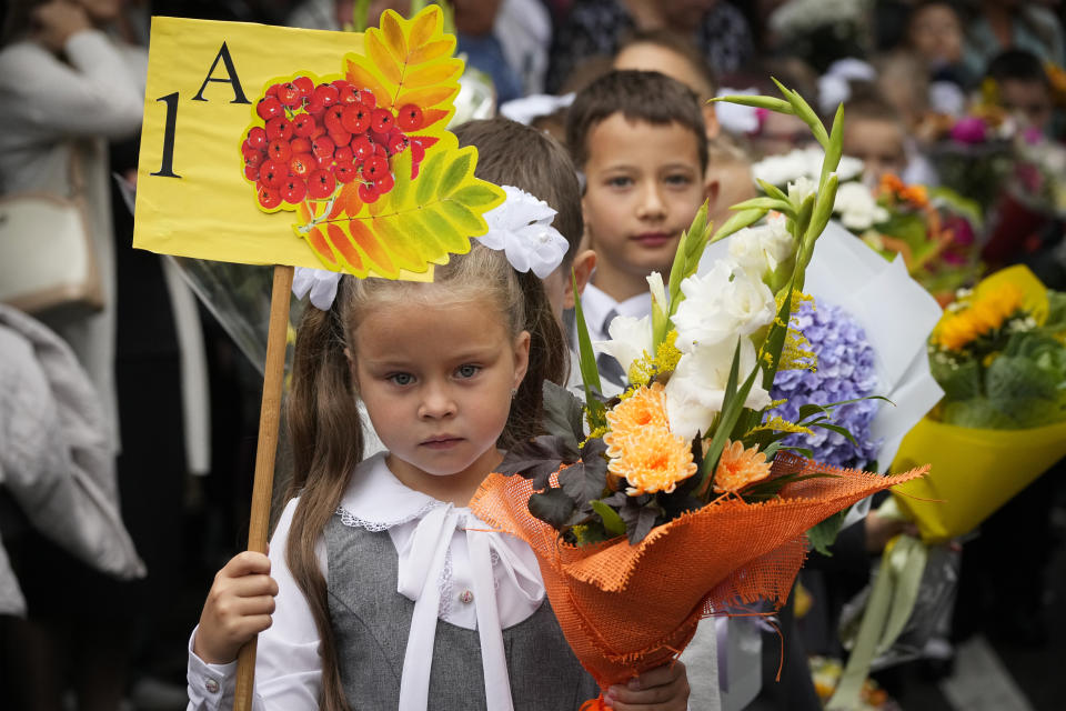 First graders take part in a ceremony marking the start of classes at a school as part of the traditional opening of the school year known as "Day of Knowledge" in St. Petersburg, Russia, Friday, Sept. 1, 2023. Many schools across the country reopen on Sept. 1. (AP Photo/Dmitri Lovetsky)