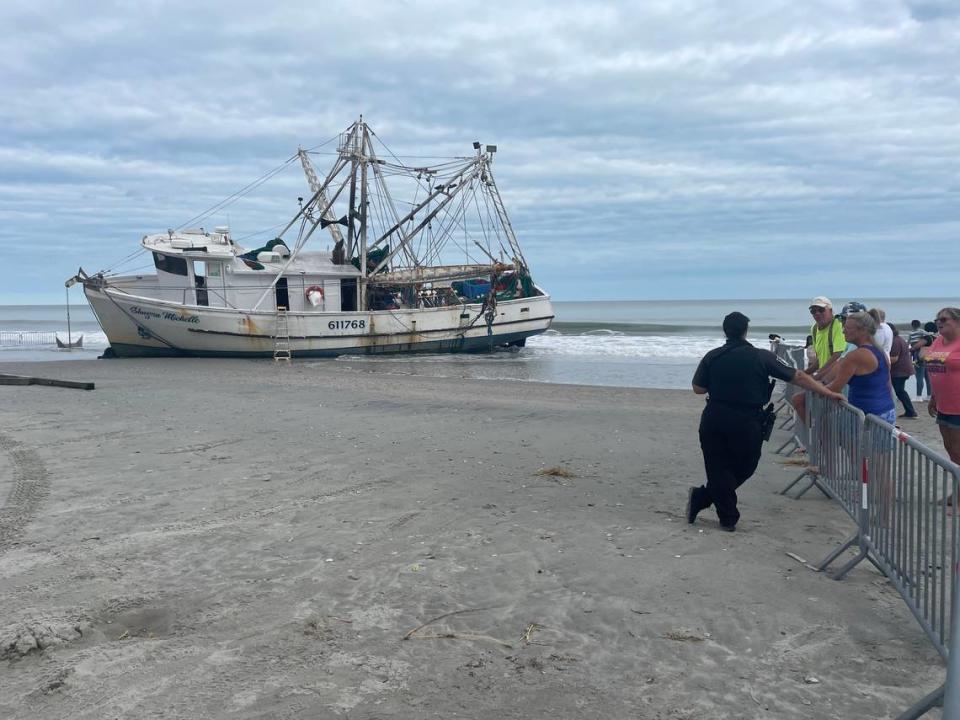 A police officer stands guard on the Shayna Michelle, a shrimp trawler that washed ashore during Hurricane Ian after losing power on Thursday. Oct. 2, 2022.