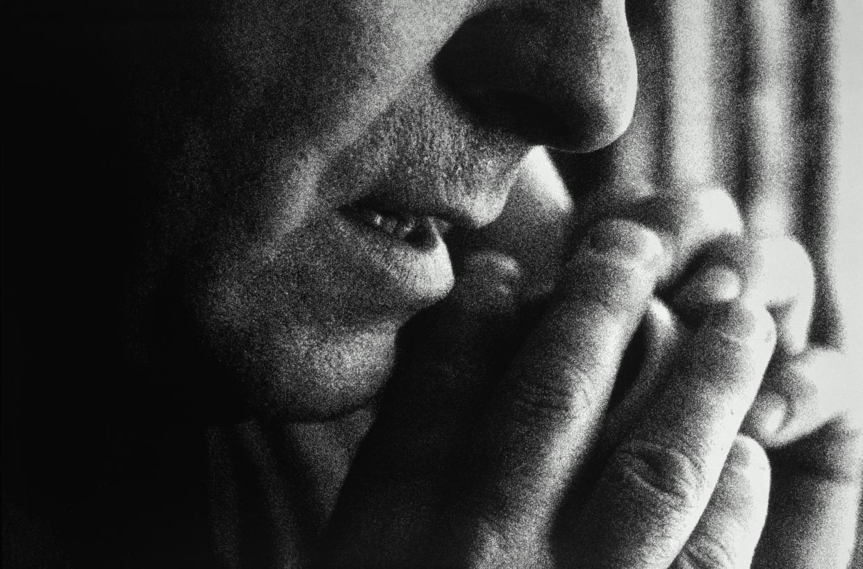 Man using telephone, covering mouthpiece with hand, (grainy B&W)